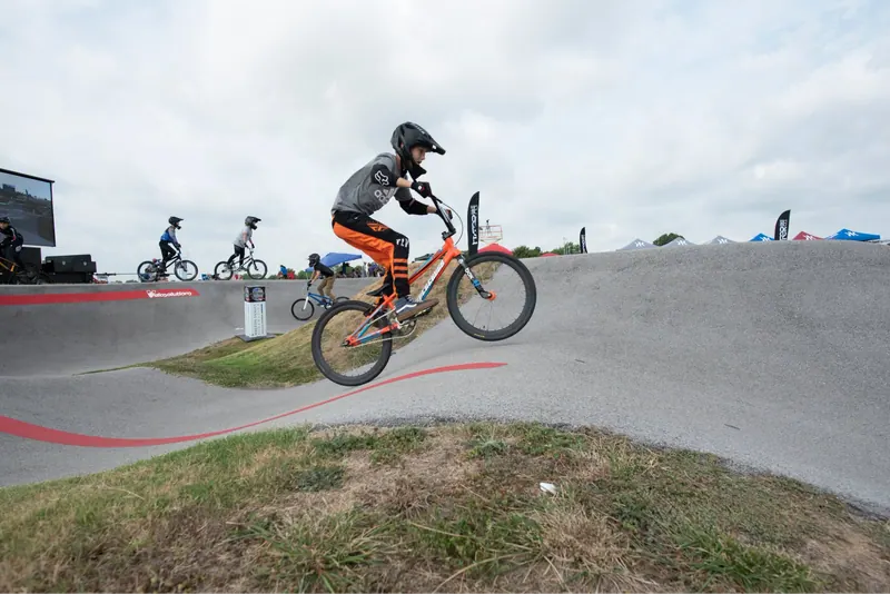 Young rider in a helmet catching air over a pump track roller