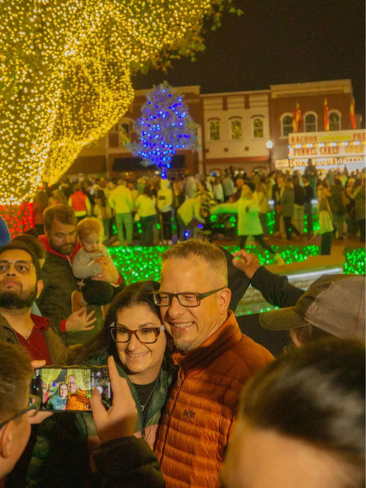 Couple taking a selfie in the crowd on the lit-up Bentonville Square