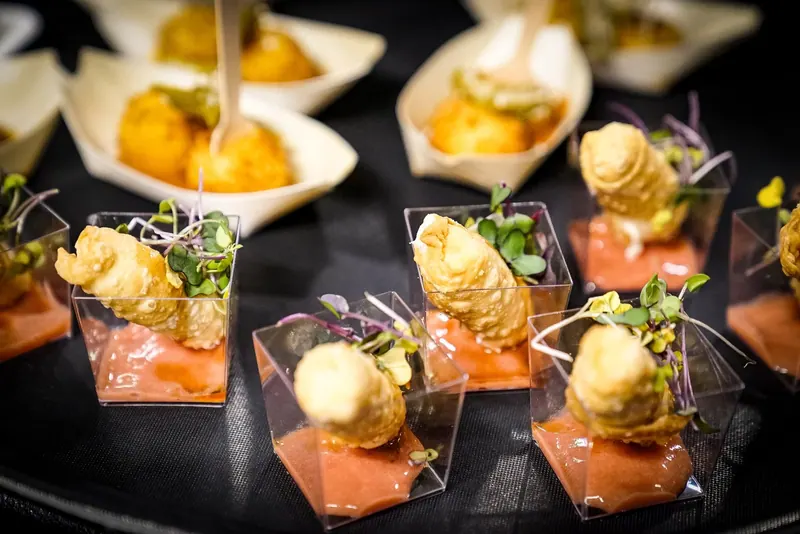 Rows of plated appetizers with fried bites and microgreens