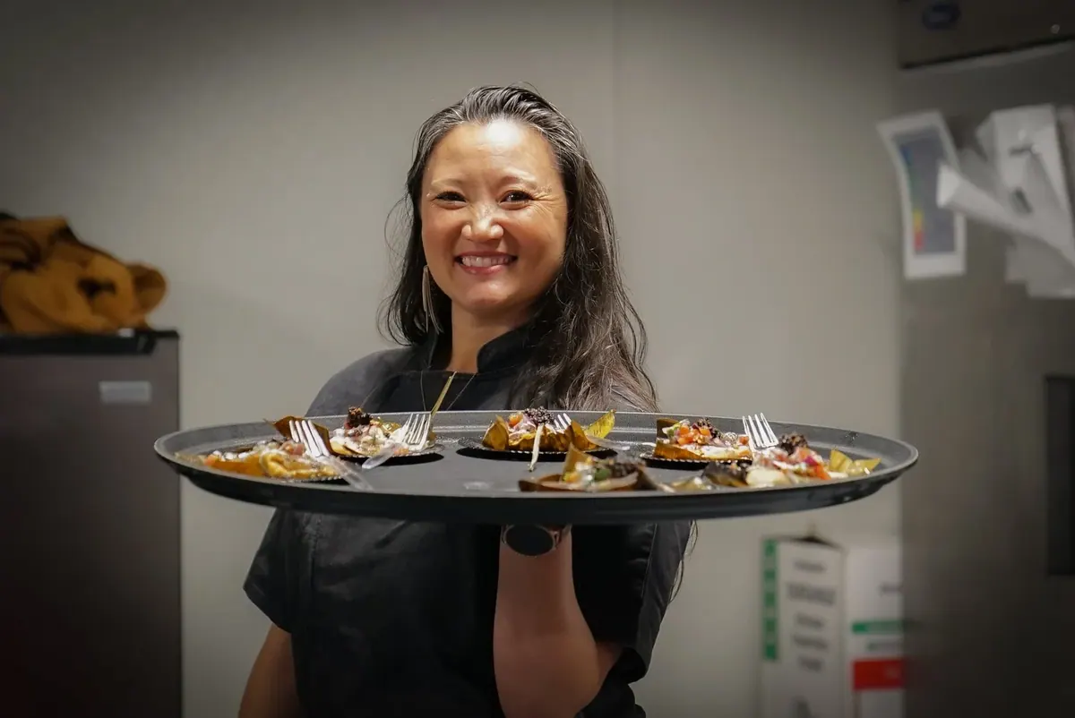 Smiling chef holding a tray of plated tasting dishes