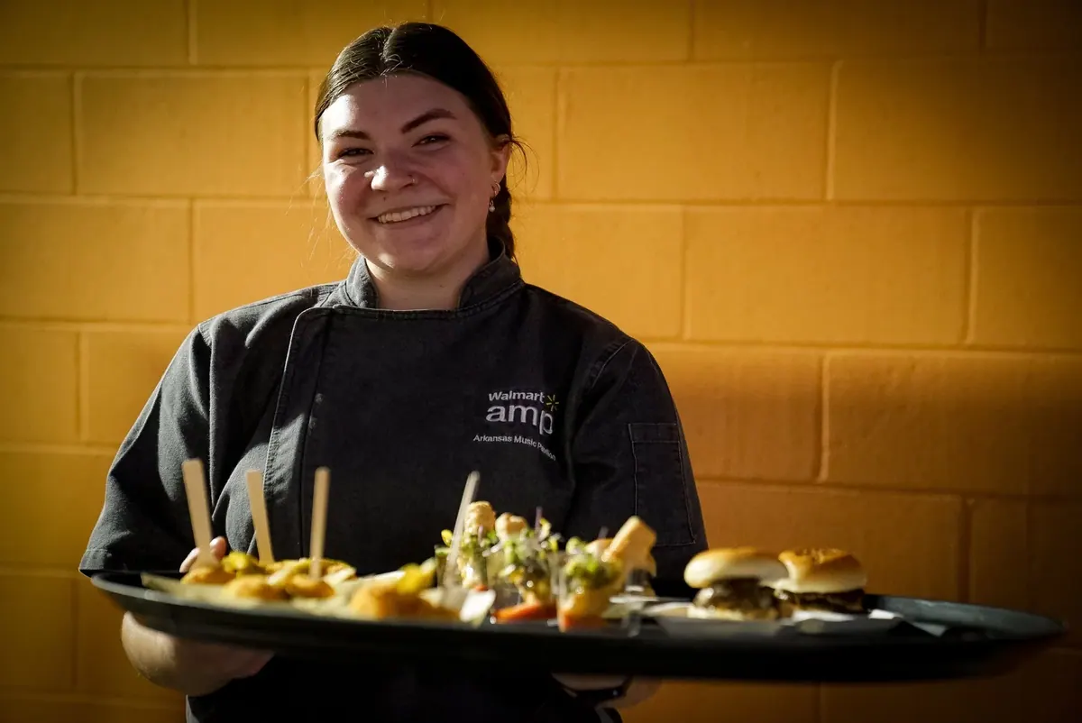 Smiling chef holding a tray of skewers and sliders