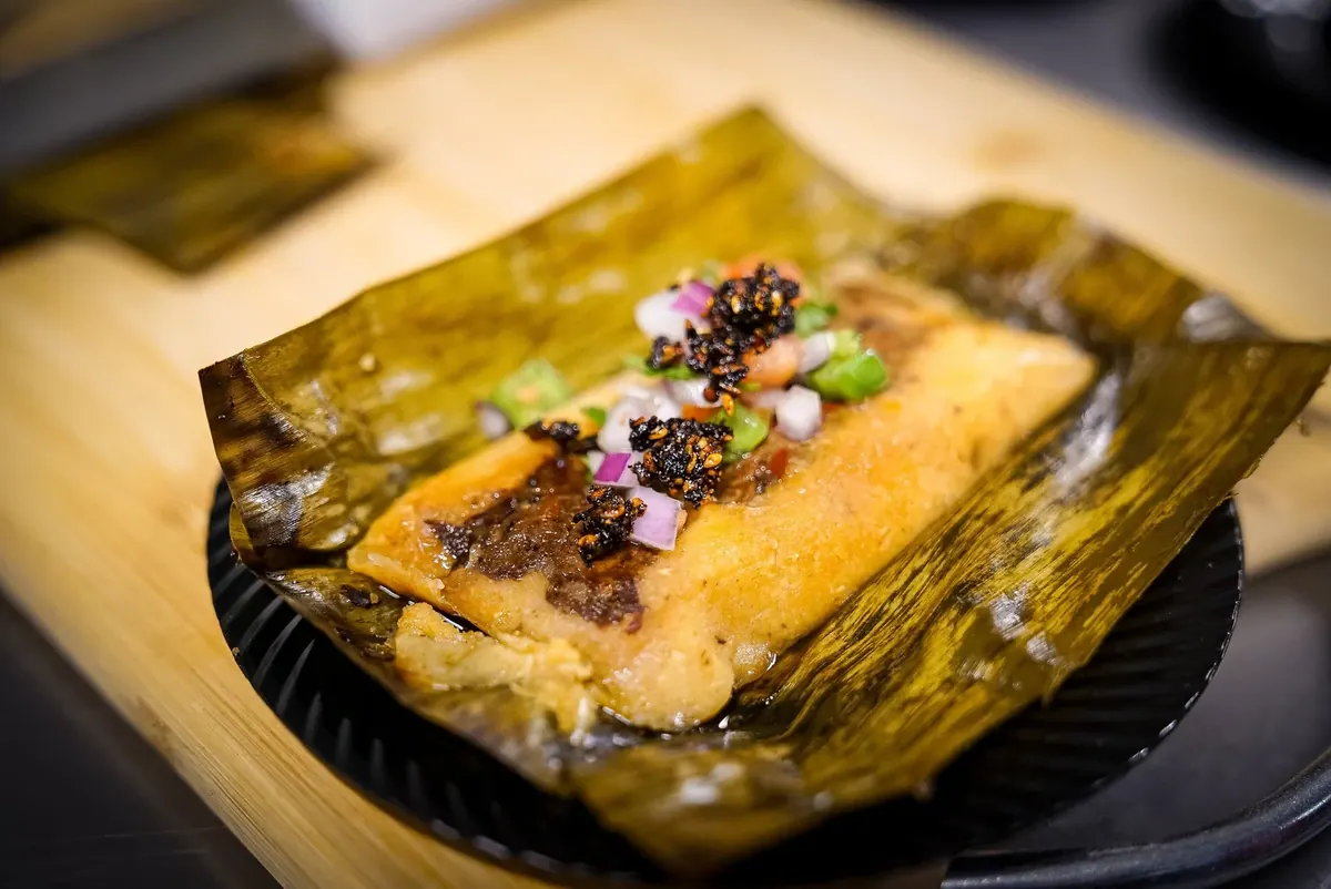 Tamale on a banana leaf topped with fresh garnish