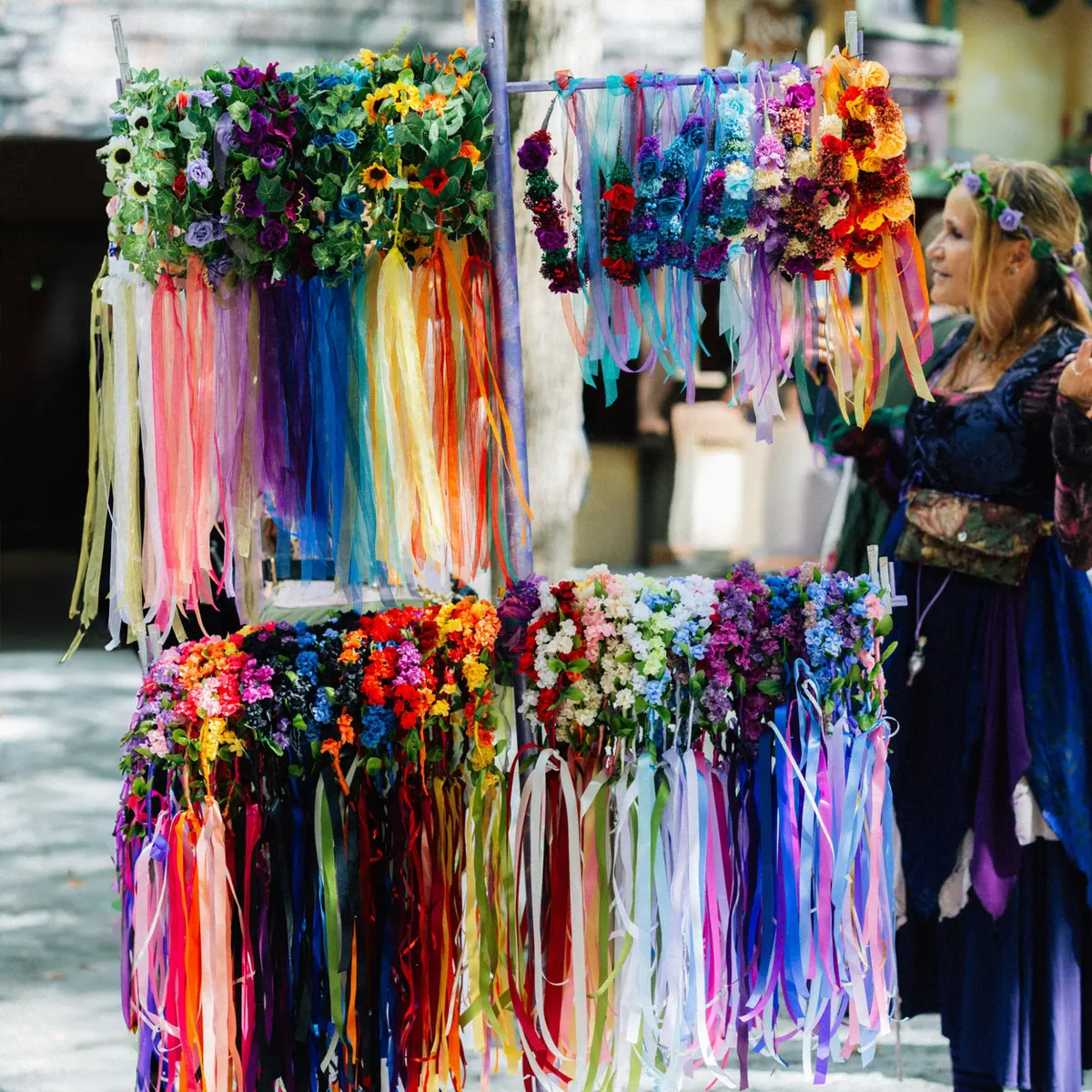 Market stall of ribboned flower crowns with a costumed vendor