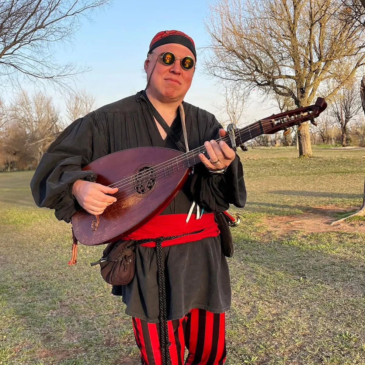 Costumed musician in a pirate outfit playing a lute