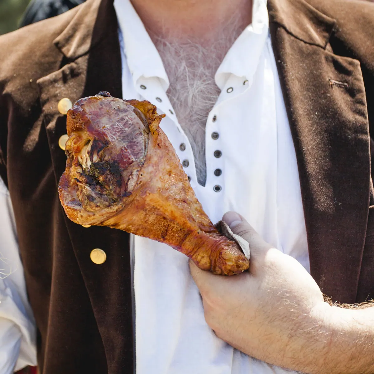 Costumed guest holding a giant roasted turkey leg