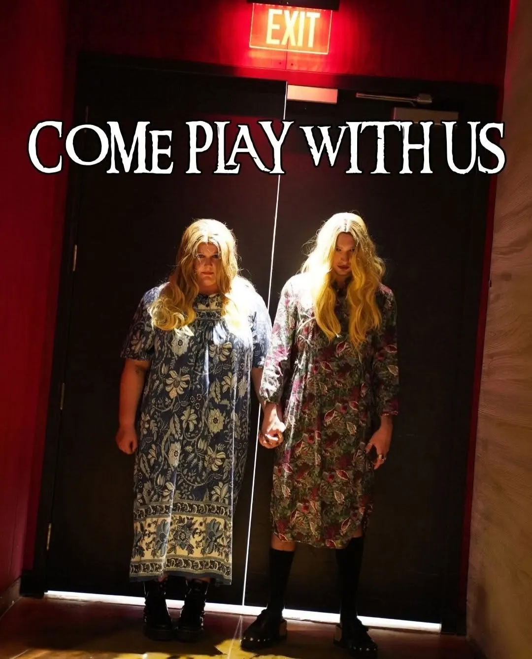 Two costumed performers holding hands in front of theater doors under the words Come Play With Us