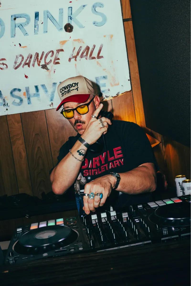 DJ Disko Cowboy mixing at a DJ controller in a cowboy hat and sunglasses